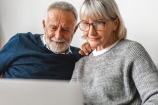 A Couple Looking At A Laptop Together