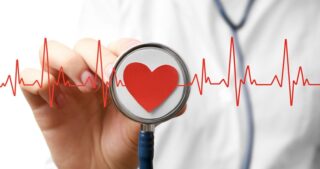 Doctor Holding A Stethoscope Superimposed With Elctrocardiogram Line And Heart Shape